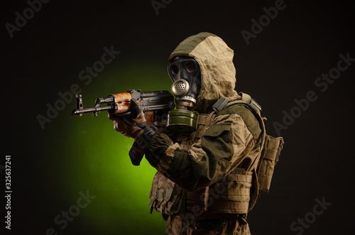 soldier Stalker saboteur in military uniform with a Kalashnikov rifle on a dark background in a gas mask