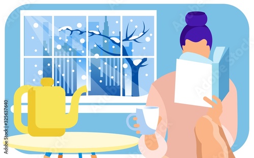 Young Woman Reading Interesting Book, Having Some Tea on Her Cozy Home Kitchen. Large Window with Snowy Winter in Big City with Skyscrapers, Office Buildings and Bare Tree Outside. Good to Be at Home.
