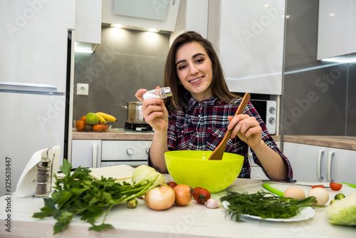 young wife preparing salad with vegetables add salt and pepper for better taste
