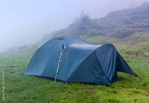 Hiking tent installed on a mountain meadow in heavy fog
