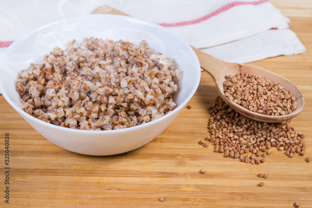 Freshly prepared buckwheat porridge against the uncooked buckwheat groat Freshly prepared buckwheat porridge against the uncooked buckwheat groat