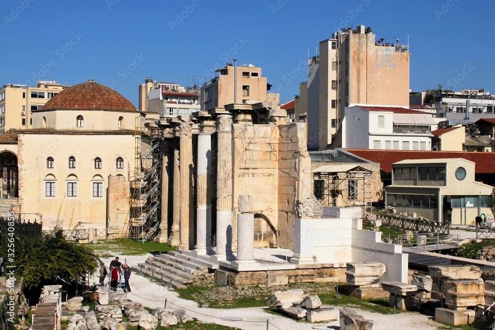 View of the archaeological site of the Hadrian's Library with an old mosque and modern buildings in the background in Athens, Greece