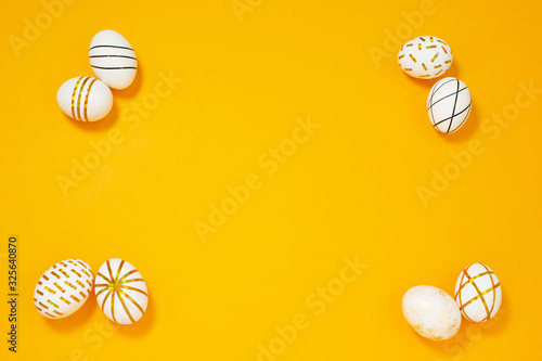 Creative golden Easter eggs on yellow background.