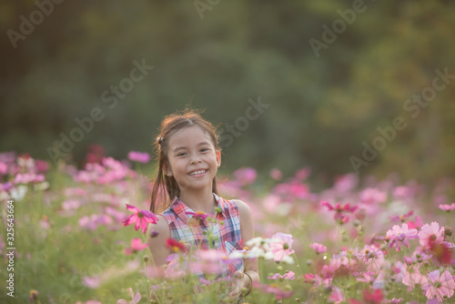 traveler or tourism. happy little asian girl child in cosmos flower fields with big smile and laughing healthy happy funny smiling face young adorable lovely female kid. happy lifestyle concept.