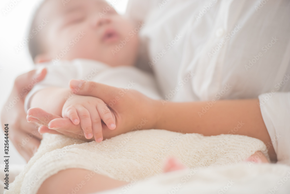 newborn baby hand while the mother is carrying in home. baby hand in mother hands. mom and her child. happy family concept. beautiful conceptual image of maternity. soft focus of baby hands and mom. newborn baby hand while the mother is carrying in home. baby hand in mother hands. mom and her child. happy family concept. beautiful conceptual image of maternity. soft focus of baby hands and mom.
