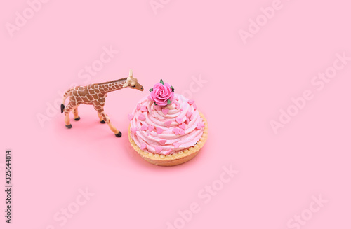 Toy giraffe and cupcake on pink background. creative minimal holiday concept. Cupcake for birthday party. copy space. spft focus photo