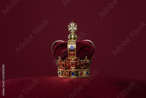 Fototapet Golden crown on a velvet cushion on a deep red background with copy space
