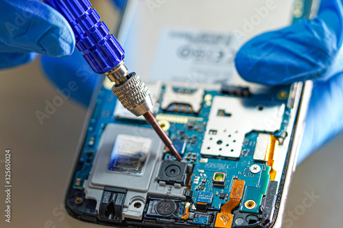 Asian Technician repairing micro circuit main board of smartphone electronic technology : computer, hardware, mobile phone, upgrade, cleaning concept.