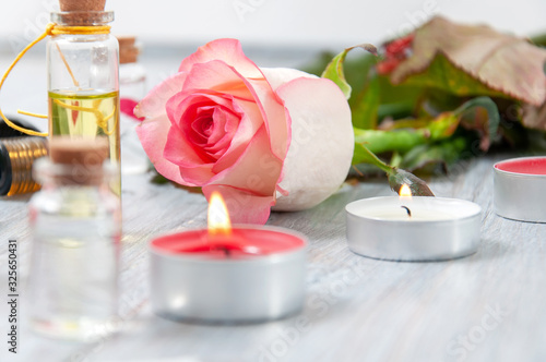 Pink roses  oil bottles and burning candles on a gray wooden table. March 8. Valentine s Day. Greeting card. Romantic and beautiful background. Spa treatments. Personal care. Love and beauty.