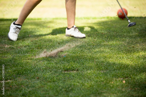 Close up golfer woman hit golf ball on green grass field