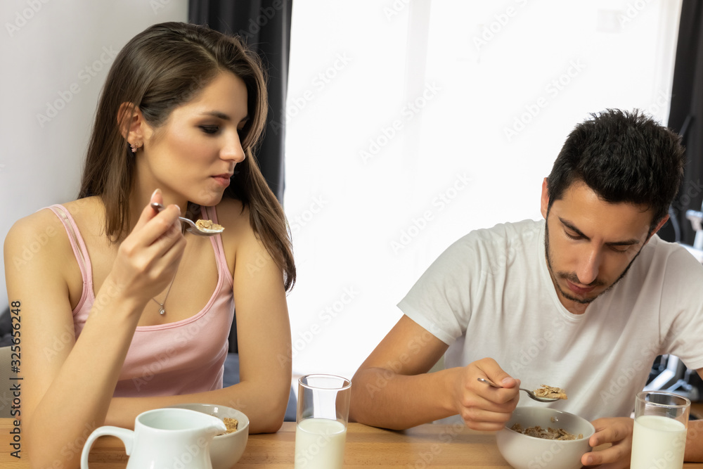 Young beautiful couple eats breakfast cereal with berries and milk. Young beautiful couple eats breakfast cereal with berries and milk.