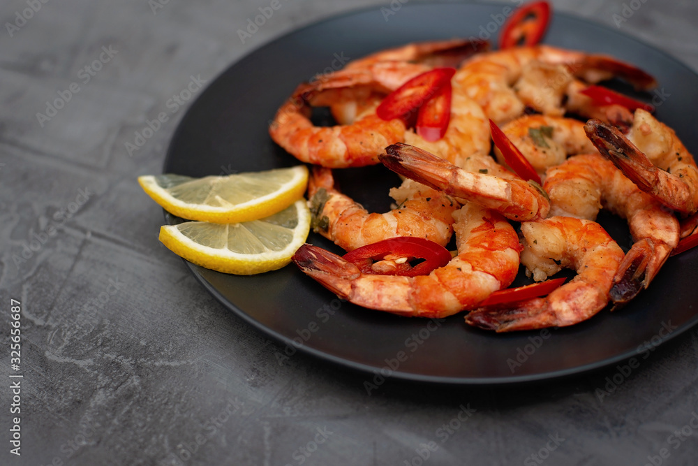 Tasty cooked fried shrimp with chilli and lemon on a gray concrete background. Healthy seafood. Flat lay. Tasty cooked fried shrimp with chilli and lemon on a gray concrete background. Healthy seafood. Flat lay.