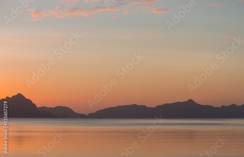Beautiful sunset soft background in Philippines  Palawan. Calm sunset at sea with islands and mountains on horizon. Evening dusk at the sea. Evening seascape panorama. Tropical lagoon in soft colors. 