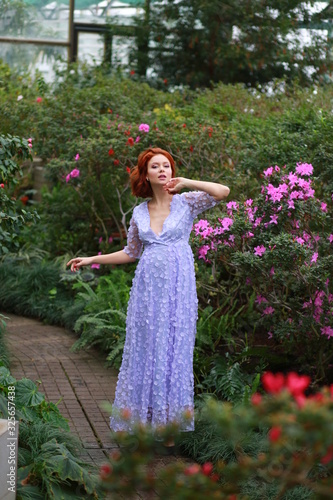 beautiful red-haired girl in arranger where azalea blooms in a colorful flying dress photo