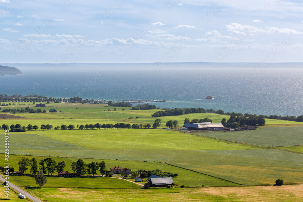 Summer rural landscape with green fields and the big lake
