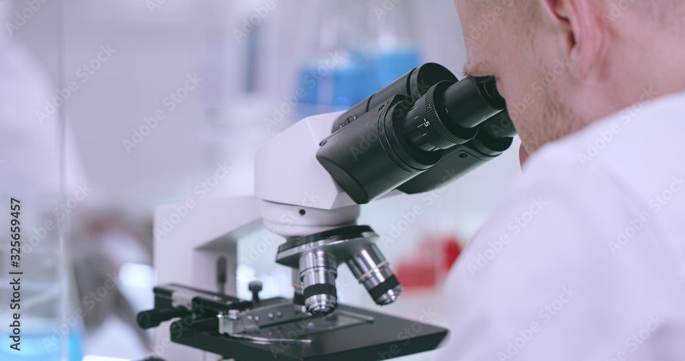 Close-up of a microscope and a working man Close-up of a microscope and a working man