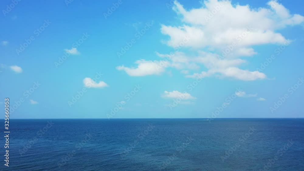 Bright sky with white clouds over the deep blue ocean and one boat sailing on the horizon. Bright sky with white clouds over the deep blue ocean and one boat sailing on the horizon.