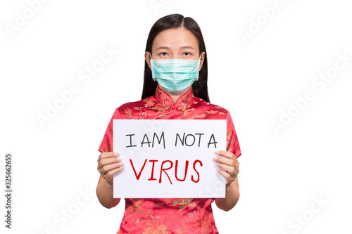 Asian woman in Chinese costume wear a hygienic mask holding sign I am not a VIRUS for anti racism , bullying and hate in the outbreak situation of Coronavirus 2019 infection or Covid-19