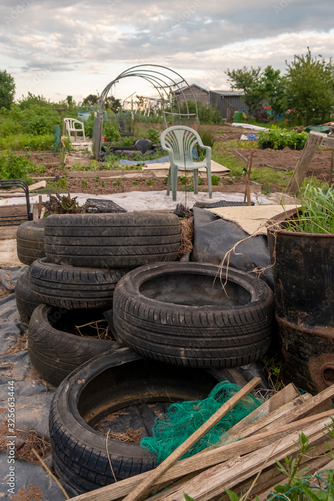 Untidy allotment with old car tyres and oil drums