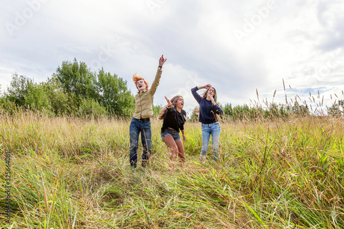 Summer holidays vacation happy people concept. Group of three friends boy and two girls dancing and having fun together outdoors. Picnic with friends on road trip in nature.