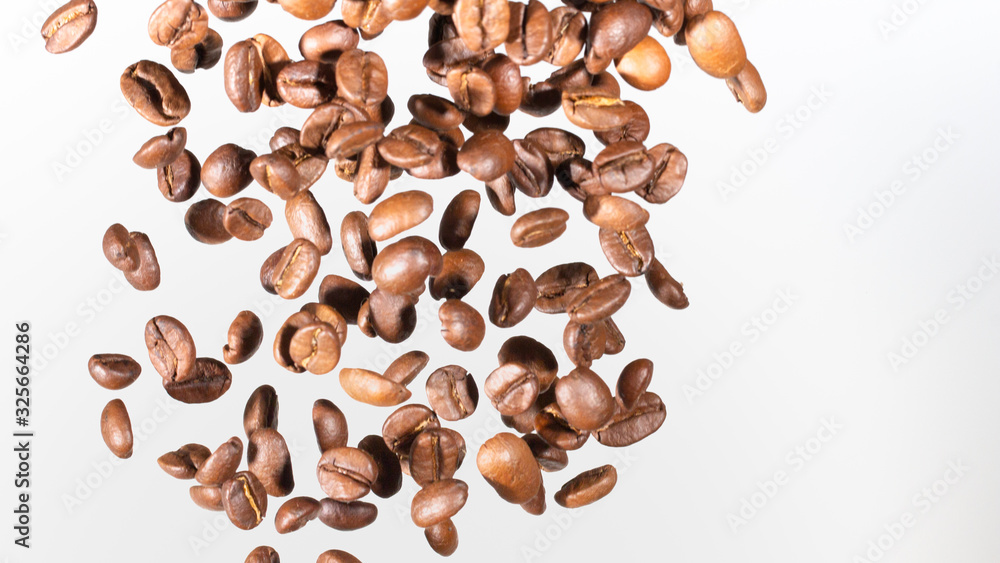 Falling coffee beans, in motion, on a white background. Selective focus. Falling coffee beans, in motion, on a white background. Selective focus.