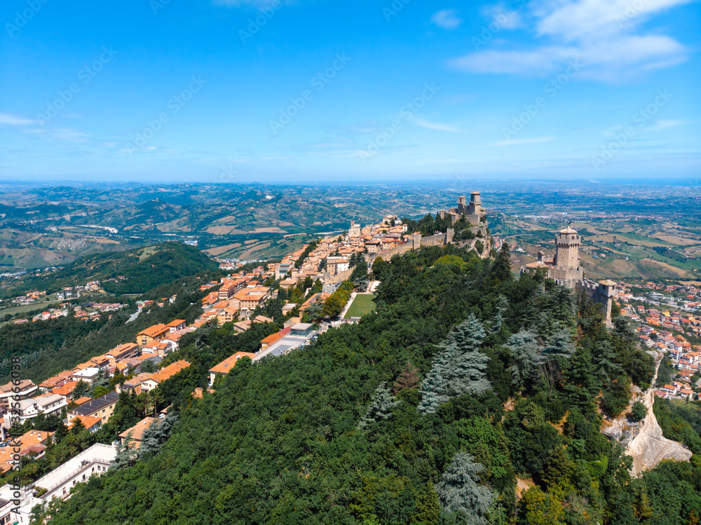 Aerial view on medieval fortress on top of the mountain, fortifications, in the background mountains and the city. The concept of the best places for tourism and holidays in Europe. San Marino, Italy