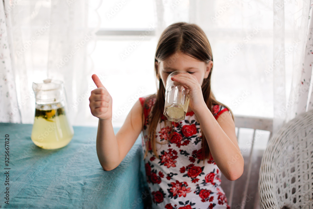 Child girl drinks homemade lemonade from glass Child girl drinks homemade lemonade from glass