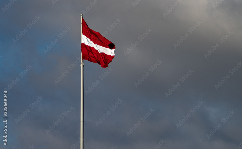 Bordeaux white flag of Latvia against a cloudy sky Bordeaux white flag of Latvia against a cloudy sky