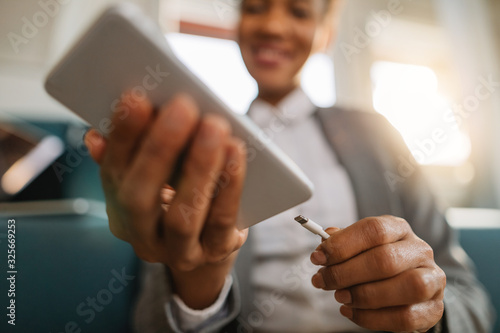 Close-up of African American businesswoman charging her mobile phone.