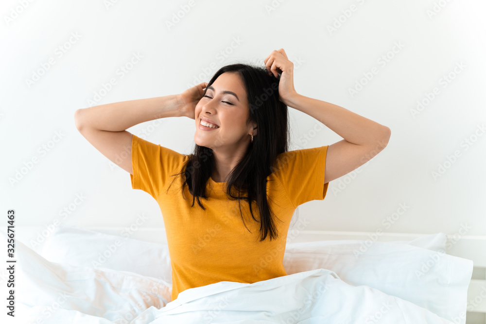 Brunette young woman in bed indoors at home. Brunette young woman in bed indoors at home.