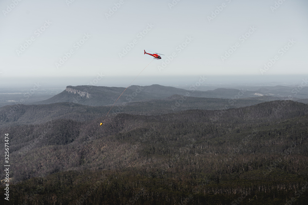 Mount Comboyne - December 30th 2019: A helicopter drops water on a spot fire as seen from the top of Mount Comboyne. Mount Comboyne - December 30th 2019: A helicopter drops water on a spot fire as seen from the top of Mount Comboyne.