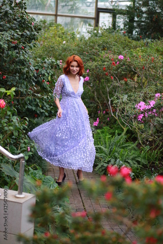 beautiful red-haired girl in arranger where azalea blooms in a colorful flying dress photo