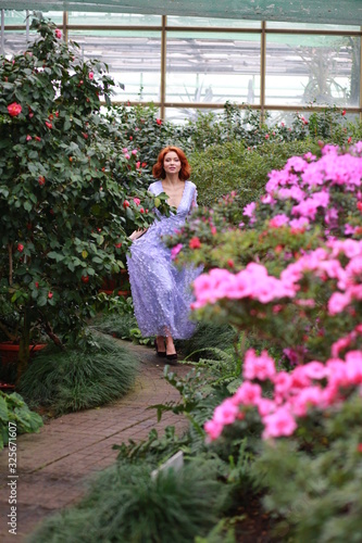 beautiful red-haired girl in arranger where azalea blooms in a colorful flying dress photo