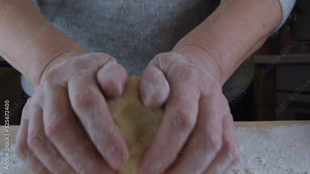 mature woman hands knead soft fresh dough in white flour on wooden board in kitchen, front view, close up mature woman hands knead soft fresh dough in white flour on wooden board in kitchen, front view, close up