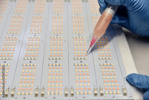 Obraz na płótnie Women in insulated gloves apply  the luminophore on SMD LED using injector and s