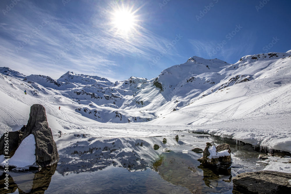 Naklejka premium Saint-Martin-de-Belleville, France - February 21, 2020: The snow-covered mountain and its reflection in Lac du Lou near Val Thorens resort