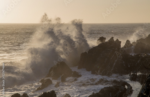 Big waves on the rocks in wintertime in a sunny day