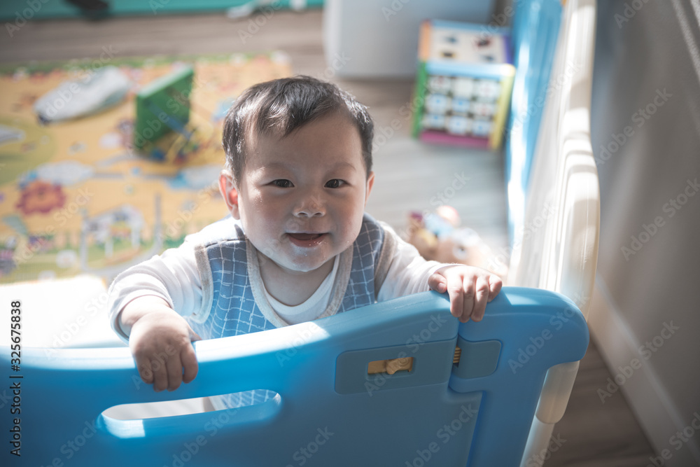 Asian baby boy standing behind safety fence waiting his mom Asian baby boy standing behind safety fence waiting his mom