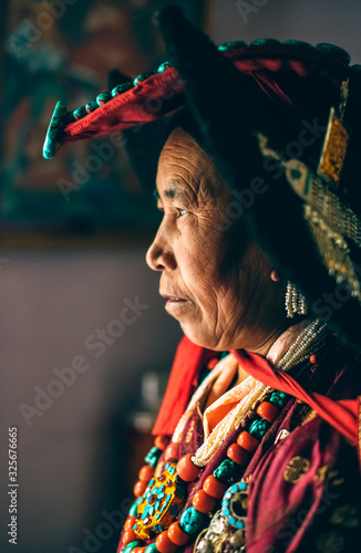 Portrait of a woman in traditional tibetan clothes inside her house in Ladakh, Kashmir, India
