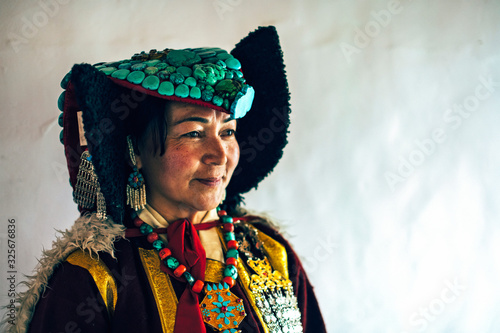 Portrait of a woman in traditional tibetan clothes inside her house in Ladakh, Kashmir, India