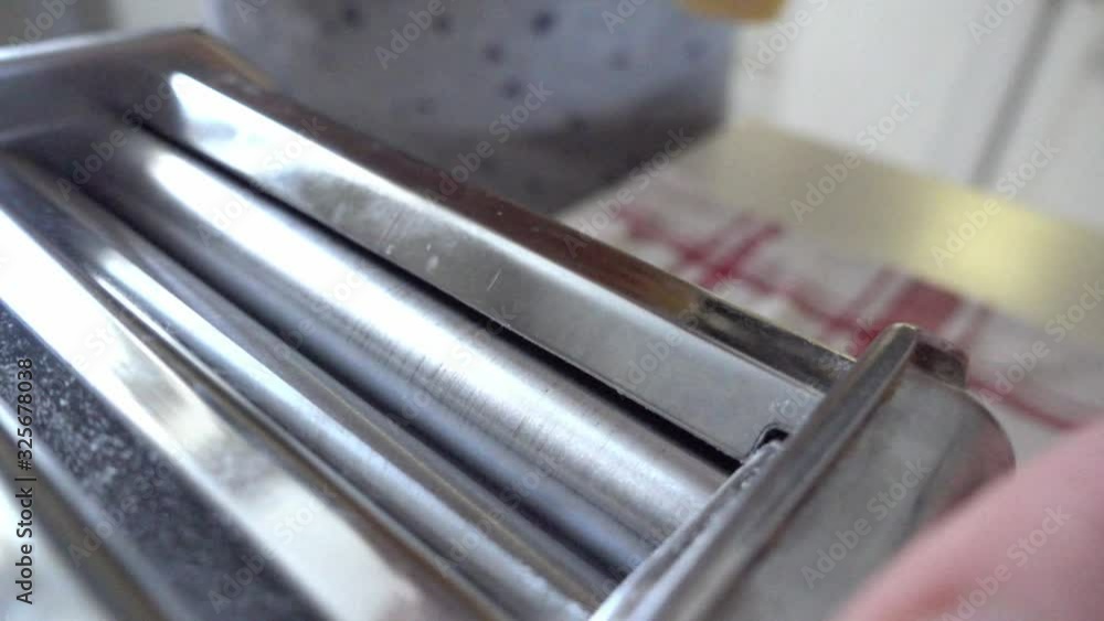 Close Up Of Pasta Sheet Being Rolled Through Machine By Hand Close Up Of Pasta Sheet Being Rolled Through Machine By Hand