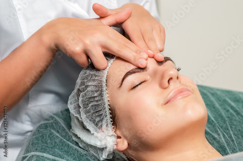 Beautiful young woman receiving face massage, close up.