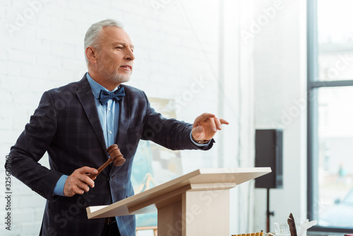 Bild auf Leinwand auctioneer holding gavel and pointing with finger during auction