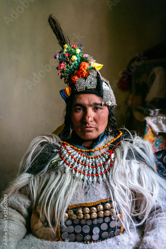 Portrait of a woman in typical tibetan clothes inside her house in Ladakh, Kashmir, India.