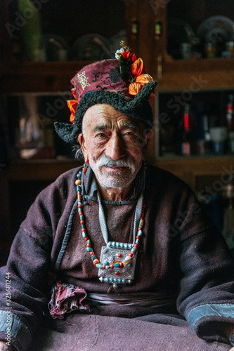 Portrait of an old man in typical tibetan clothes inside his house in Ladakh, Kashmir, India.