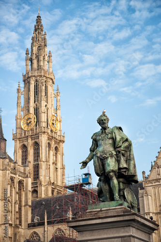 Vertical view of bell tower of Cathedral of Our Lady in Antwerp, UNESCO world heritage site in Belgium with statue of Pieter Paul Rubens with pigeon on his head in front. Travel tourism in Benelux.