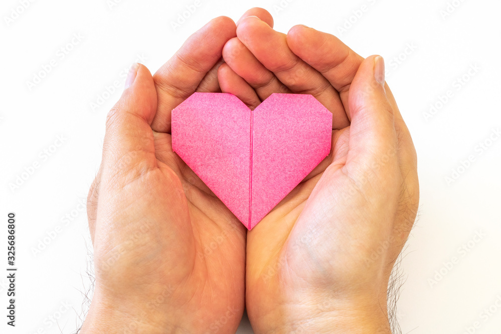 Obraz premium 折り紙で作ったハートを持つ男の手