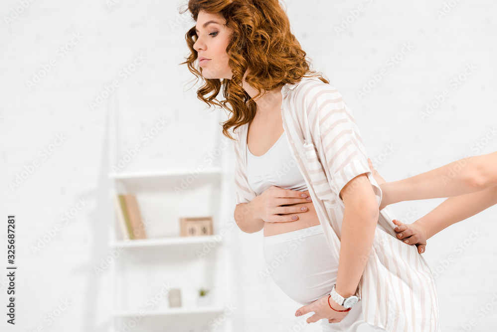 Side view of masseur doing lower back massage to pregnant woman Side view of masseur doing lower back massage to pregnant woman