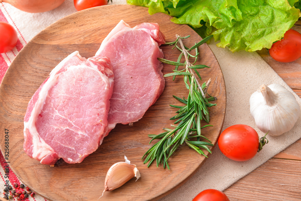 Plate with raw pork meat and vegetables on table Plate with raw pork meat and vegetables on table