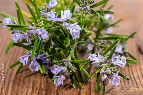 Extreme close-up view of fresh purple blooming rosemary twigs on a rustic wooden background